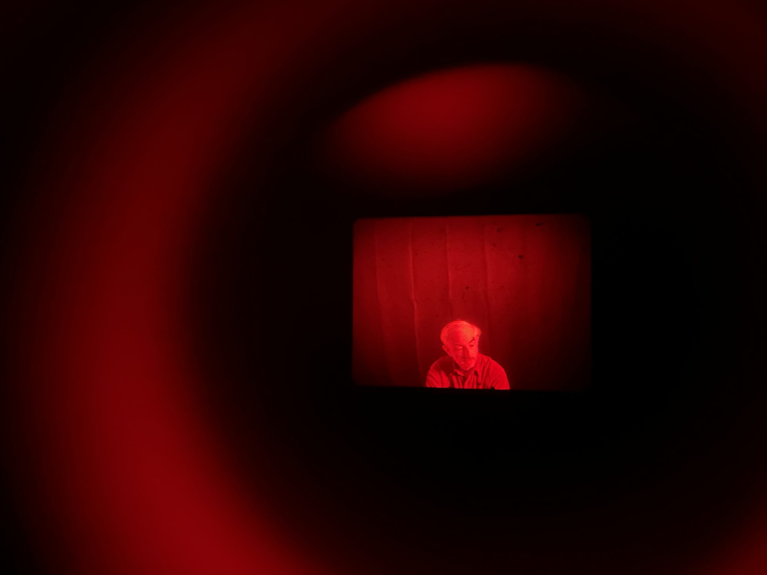 Abstract red tinged image of a man through a viewinder