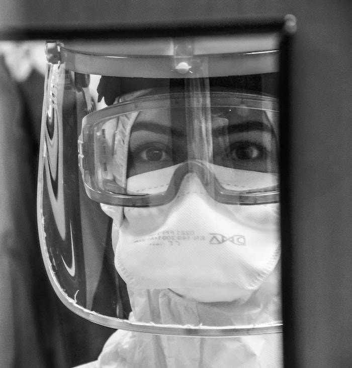 Close of up a woman's face wearing full Covid protective clothing